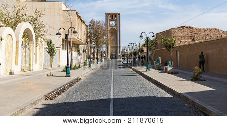 Yazd, Iran - October 10, 2016: A Woman Wearing Traditional Clothes Passes Clock Tower At Hazrat Mahd