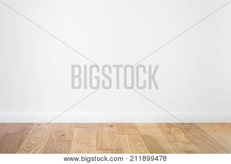 White painted stucco wall and natural wooden ash-tree 3-band parquet board hardwood floor. Flooring in scandinavian style of empty interior with wide white baseboards.