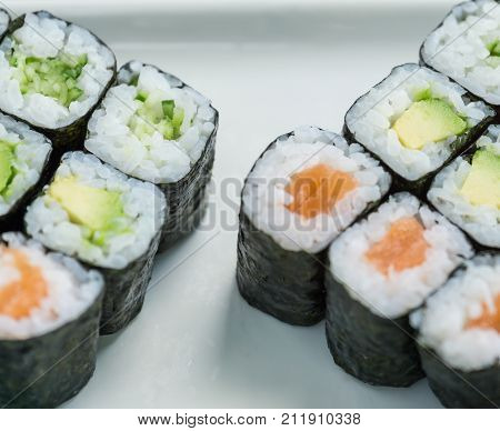 Sushi with salmon and avocado on white plate