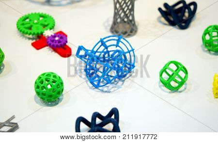 Many abstract models bright colorful objects printed on a 3d printer on a white table. Fused deposition modeling, FDM. Progressive modern additive technology. Concept of 4.0 industrial revolution