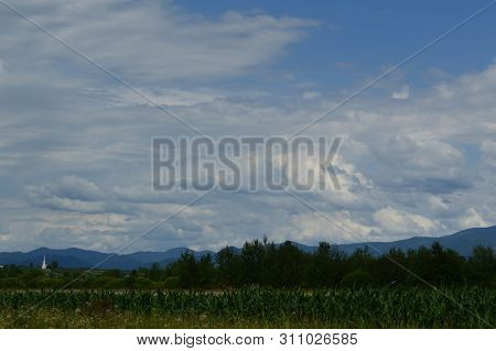 Mountain Landscape With Green Meadows And Leafy Trees Under Cloudy Sky In Fundatura Ponorului, Roman