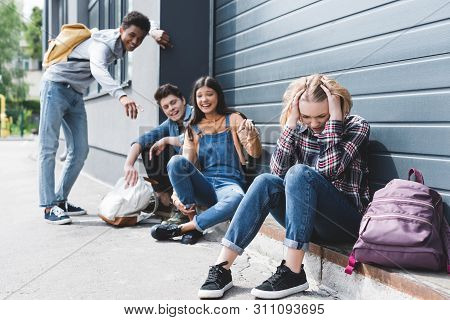 Smiling Friends Bulling And Pointing With Fingers At Sad Blonde Teen