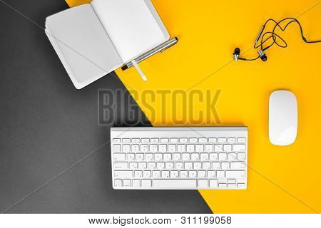 Office Workplace Minimal Concept. Computer Keyboard With Blank Notebook, Pen, Headphones On Black & 