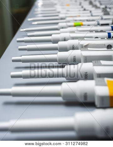 Row Of Pipettes Turned On Their Sides On A Grey Table Top After Being Cleaned.