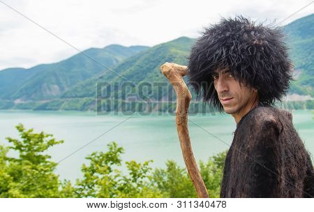 Georgian Man In A Beech Costume On A Background Of Mountains. Selective Focus.