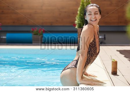Side View Of Young Woman Relaxing In Swimming Pool. Beautiful Caucasian Female With Wet Hair In Swim