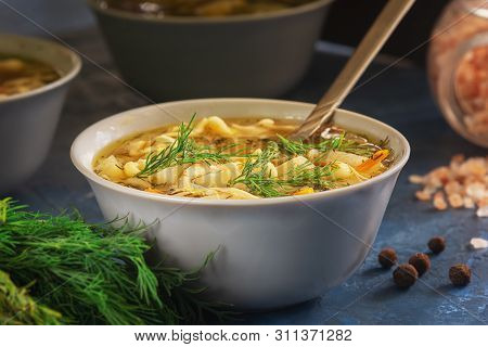 Chicken Noodle Clear Soup Bowl Closeup Hot Lunch. Healthy Meat Broth In White Dish With Spoon. Homem