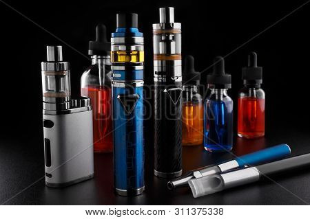 Electronic Cigarettes And Bottles With Vape Liquid On Black Background