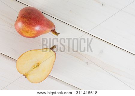 Group Of One Whole One Half Of Fresh Dark Red Pear Anjou Flatlay On White Wood
