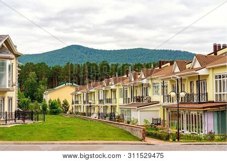 A Row Of Just Finished New Yellow Townhouses. Residential Village At The Foot Of The Mountains.