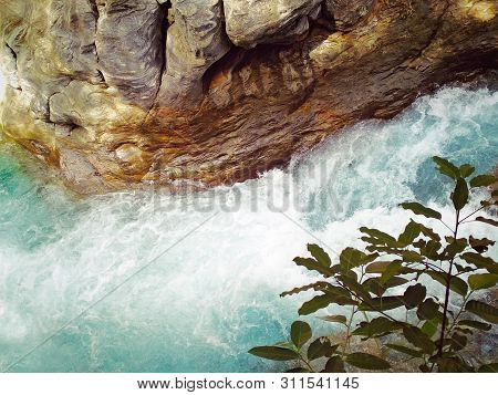 Clear Exotic Azure Blue River Flowing Through Beautifully Shaped And Colored Rocks And Stones, Surro