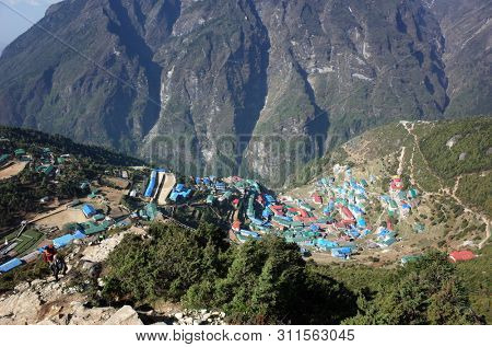 Namche Bazaar, Nepal - May 12, 2019: Tourist and guide hiking up trail to viewpoint from Namche Bazaar village in Sagarmatha national park, Khumbu valley, Himalayas