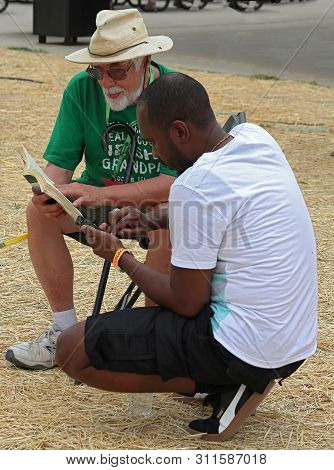 Littleton, Colorado - July 13, 2019: Two Men, Old And Young, Discussing A Book On Colorado Irish Fes