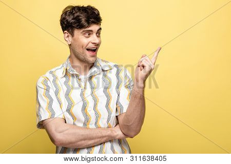 Cheerful Young Man Looking Pointing With Finger While Looking Away On Yellow Background