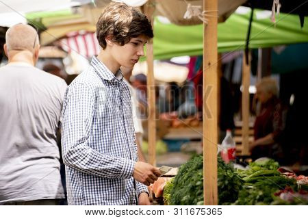 Young Pesron Choose Fresh Ripe Veggies At The Outdoor Market And Purchasing It
