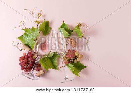 Assorted Wineglasses With Rose And White Wine, Grape, Leaves And Cork Lying On Pink Background. Wine
