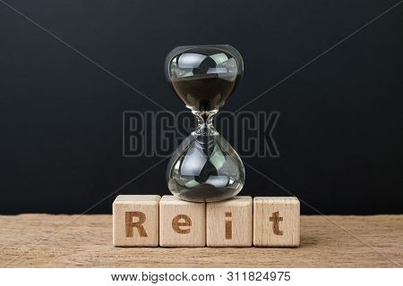 Reit, Real Estate Investment Trust Booming Time Concept, Sandglass Or Hourglass On Wooden Cube Block