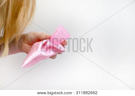 A Woman Holds A Menstrual Cup In Her Hand On A Pink Background. The Concept Of Women's Health, Hygie