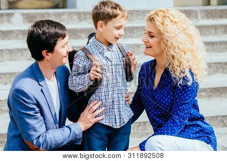 Enjoying Family Concept. Happy Mom And Dad Sending Their Child Pupil Boy First Time Studing To Schoo