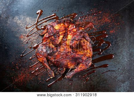 Barbecue spatchcocked barbecue chicken al mattone with hot chili sauce as top view on an old metal sheet 