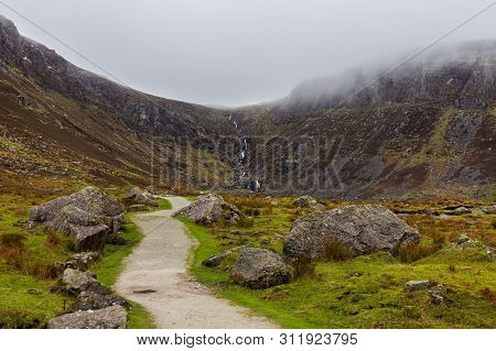 Path Winding Through A Boulder Strewn Valley Leading To Mahon Falls In Waterford County, Ireland