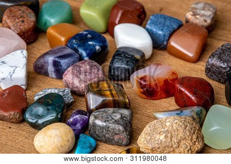 Collection Of Different Colored Polished Gemstones An Jewels On Wooden Underground