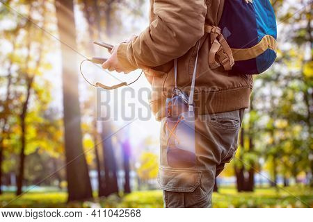 Man Hiker In The Forest Is Charging A Smartphone With A Portable Charger. Power Bank In A Man's Hand