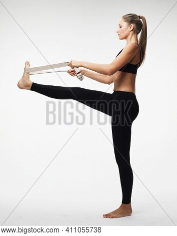 Motivation, fitness and people concept: Sporty young woman doing a exersize with resistance band. Photo of young woman in fashionable sportswear on white background.