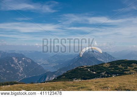 Athlete With The White-and-yellow Parachute Runs And Then Soars Over Mount Krippenstein In Upper Aus