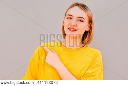 Horizontal Picture Of Young Good-looking Female Isolated On Grey Background, Pointing Leftwards With