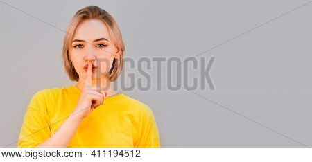 Portrait Of A Stylish And Calm Young Woman In A Yellow Sweater, Looking Into The Camera, Asking For