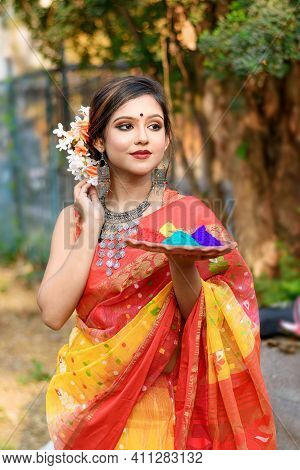 Portrait Of Pretty Young Indian Girl Wearing Traditional Saree And Jewellery, Holding Powder Colours