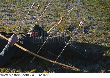 Man Lying On A Frozen Lawn Hit By An Arrow From A Bow. Archery Range With Rules To Prevent Injury Or
