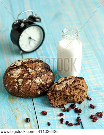 Dark Rye Bread Loaf With Crispy Crust, Glass Of Milk And Alarm Clock. Freshly Bakery Food In Working