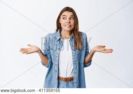 Oops Sorry. Clueless Young Woman Shrugging And Looking Away Unsure, Dont Know And Have No Idea, Noth