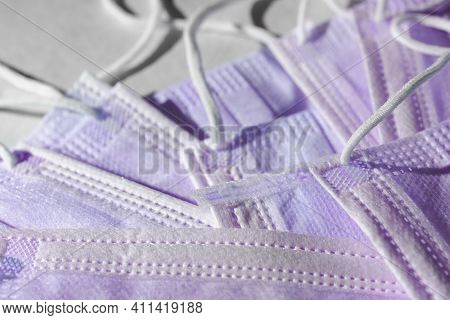 Many Disposable 3-ply Purple Face Masks In A Pile. Elastic Ear Loop Style Masks Often Associated Wit