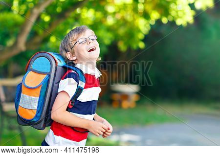 Happy Little Kid Boy With Glasses And Backpack Or Satchel On His First Day To School Or Nursery. Chi