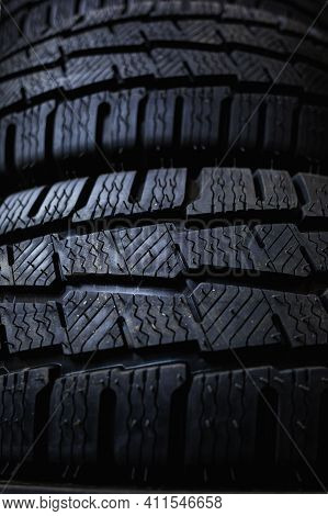Tires close up. Black studdable winter tyre profile. Car tires in a row.