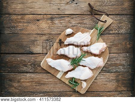 Raw Chicken Wings With Skin On Cutting Board With Ingredients For Cooking At Wooden Background. Fres