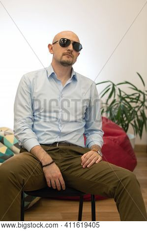 Baldheaded Bearded Brutal Man In Sunglasses Sitting On Chair