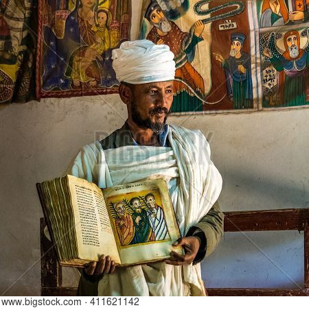Yeha, Ethiopia - Feb 10, 2020: An Orthodox Priest Shows A Painted Holy Bible From The 14th Century I