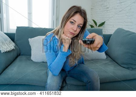 Bored Woman Watching Tv At Home Changing Channels With Remote Control