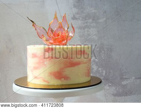 An Edible Red Isomalt Flower On Top Of A Cake On A Light Concrete Background