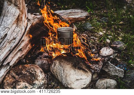 Kettle Hanging Over Fire. Cooking Food At Fire In Wild. Beautiful Big Log Burns In Bonfire Close-up.