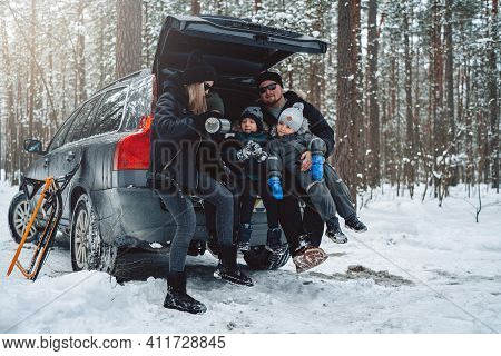 Vacations And Enjoynment Of A Caucasian Family. Three Boys With Their Parents Sit On Car Trunk In Wi