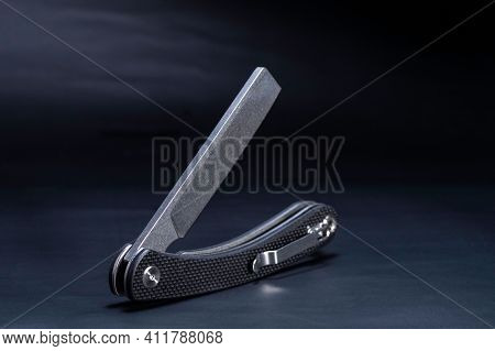 Knife With A Clip On The Handle. The Knife Is In An Unusual Position. Pocket Knife With Clip.