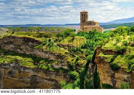 Church On The Edge Of The Precipice In A Green Field With Cloudy Sky. Sepulveda, Segovia, Spain.