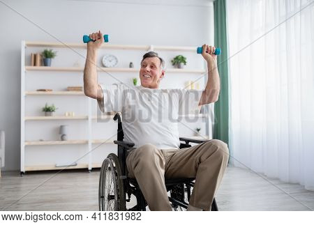 Physical Activities For Disabled Elderly Adults. Happy Handicapped Man In Wheelchair Making Rehabili