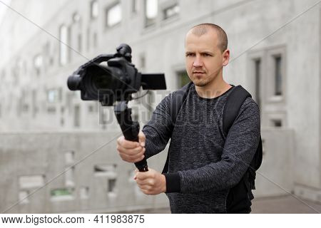 Professional Videographer Shooting Video Using Modern Dslr Camera On 3-axis Gimbal Over Grey Concret
