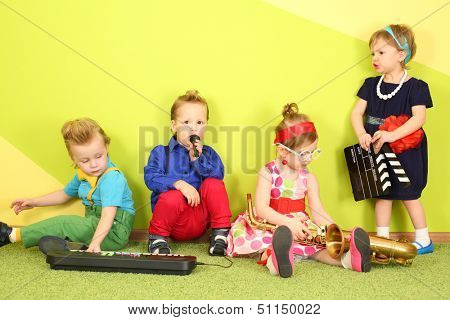 Mods two girls and two boys at the bright green wall with a trumpet and a toy piano